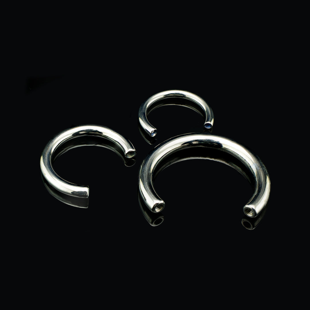Three silver colors circular shaped bars with a small opening at the bottom for threaded ends to be attached. Set on a black background.