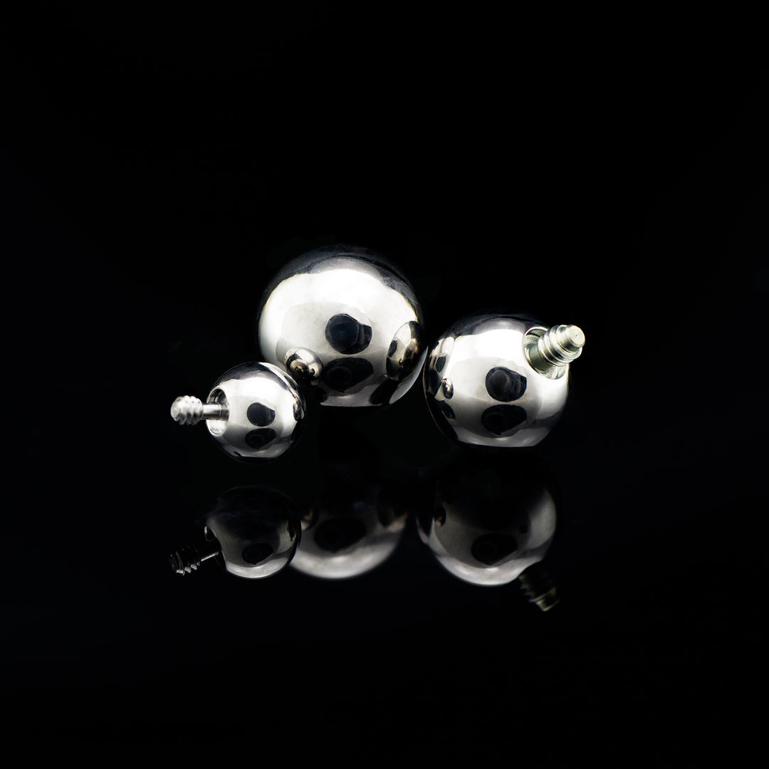 Three silver colored beads with threaded attached varying in size on a black background.