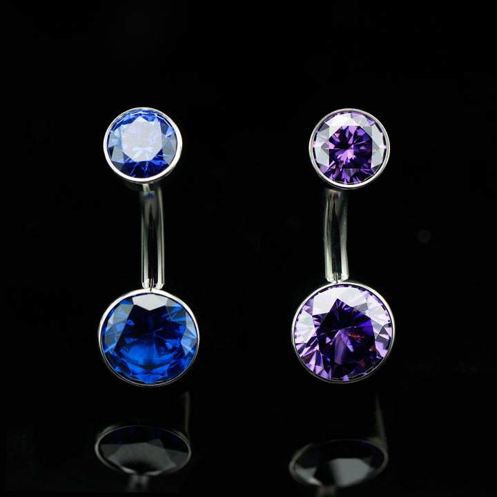 Two navel curves on a black background. One with deep blue stones on the top and bottom and another with deep purple stones on the top and bottom.