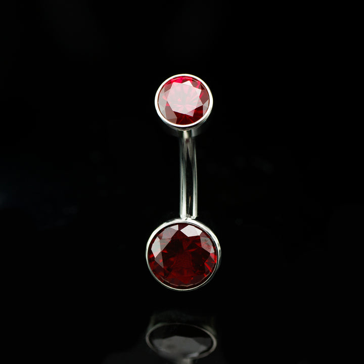 Navel curve with two dark red stones, one at the top and one on the bottom.