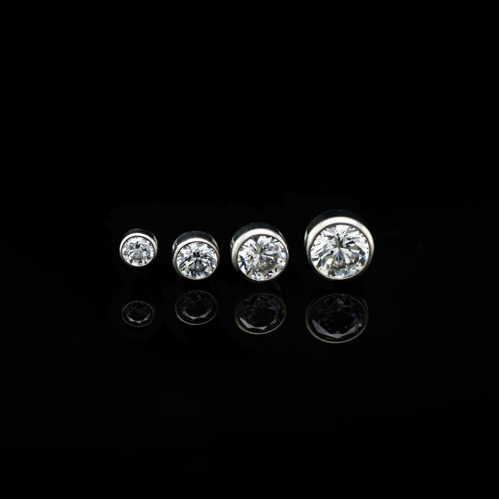 Row of four bezel set white cubic zirconia in varying sizes on a black background.