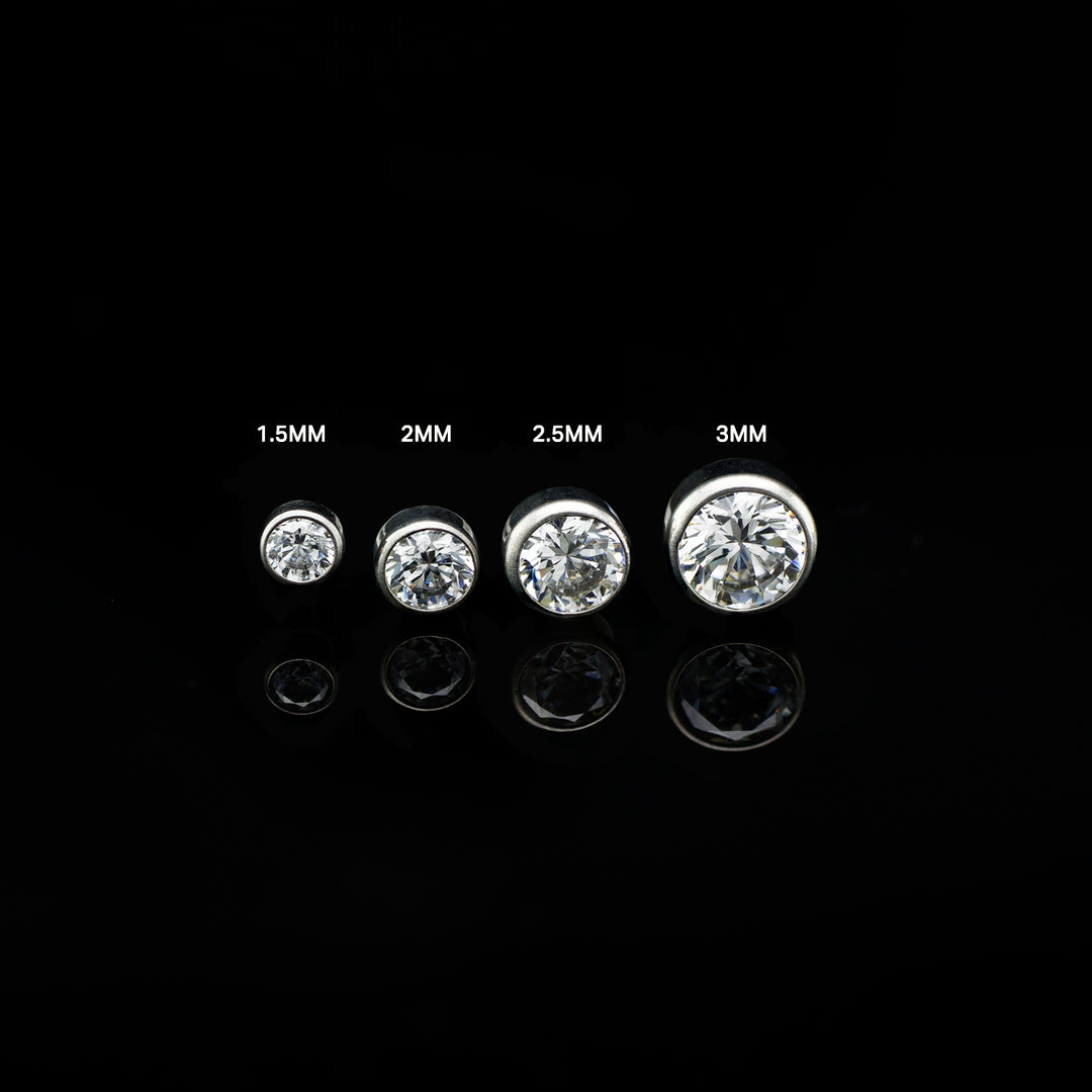 Row of four bezel set white cubic zirconia in varying sizes on a black background. The pieces are size labeled from left to right in ascending sizes.