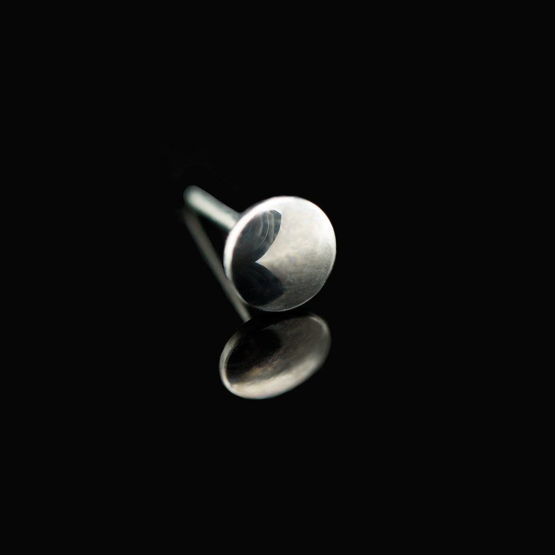 A silver color round disk jewelry piece set on a black background.