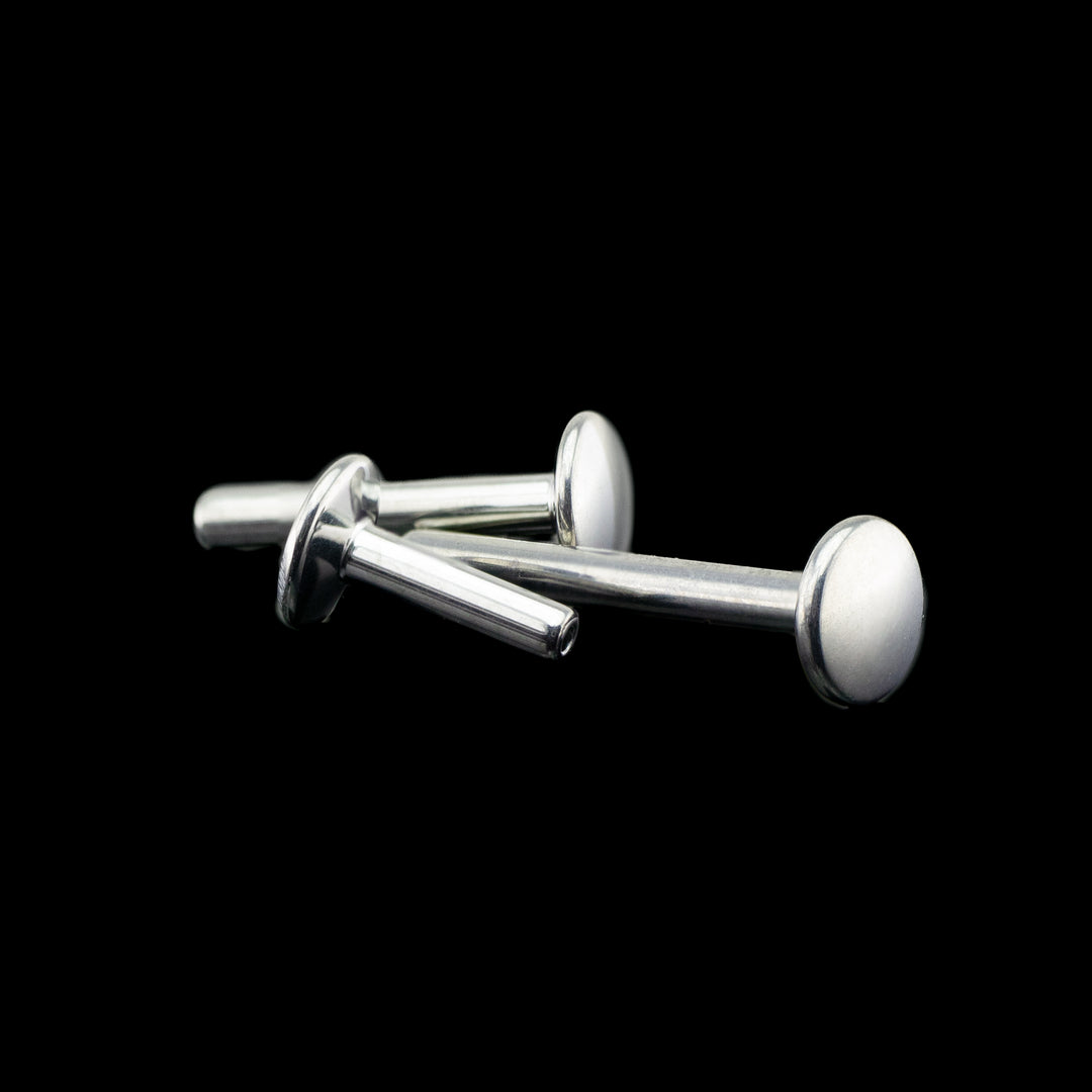 Three flat back push pin style posts on a black background. The posts are laying on their sides showing various angles. the whole piece is high polished to a mirror finish.