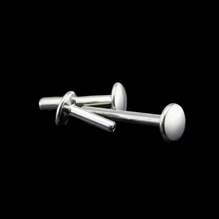 Three flat back push pin style posts on a black background. The posts are laying on their sides showing various angles. the whole piece is high polished to a mirror finish.