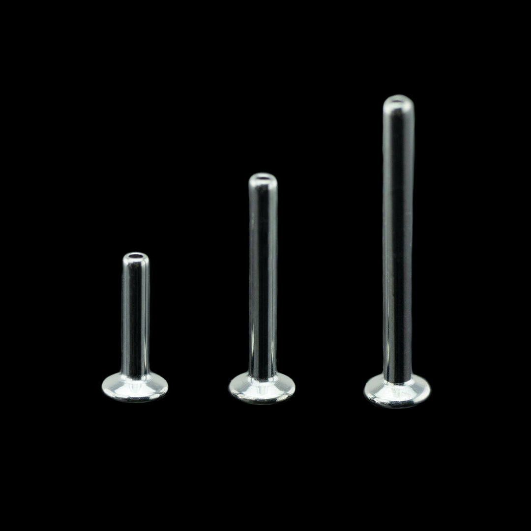 Three flat back push pin style posts on a black background. pictured from left to right in ascending lengths to show the range of sizes. These posts have a smaller disk back making them great for piercings that are close together or piercings in areas with little room like nose piercings and forward helix piercings.
These disks are high polished to a mirror finish.