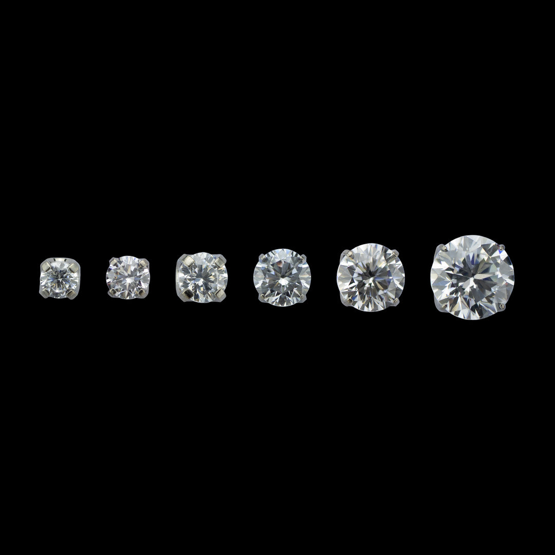 6 pieces of implant grade titanium body jewelry. Shown from left to right in ascending sizes. Each piece is a solitaire white cubic zirconia set in four prongs.