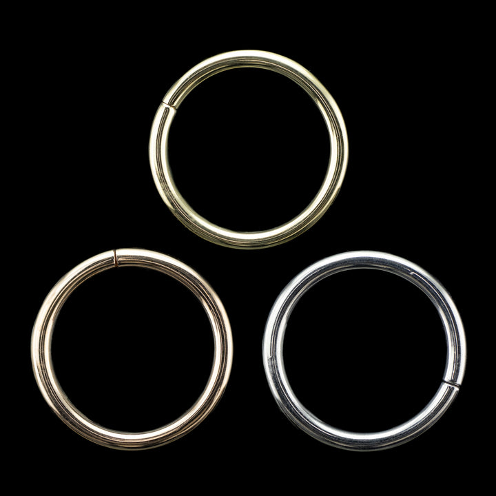 Solid gold seamless hoops on a black background. One in rose gold, one in yellow gold, and one in white gold. 3 simple high polish rings for belly, navel, nostril, daith, cartilage, helix, rook, tragus, earlobe piercings.