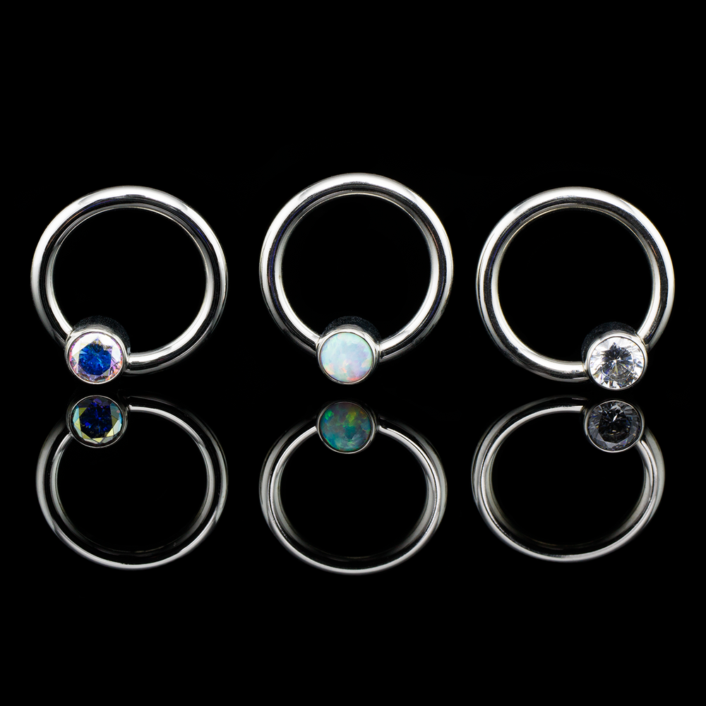 Thre silver colored fixed bead rings with captive gems in varying colors in each.
Septum, Daith