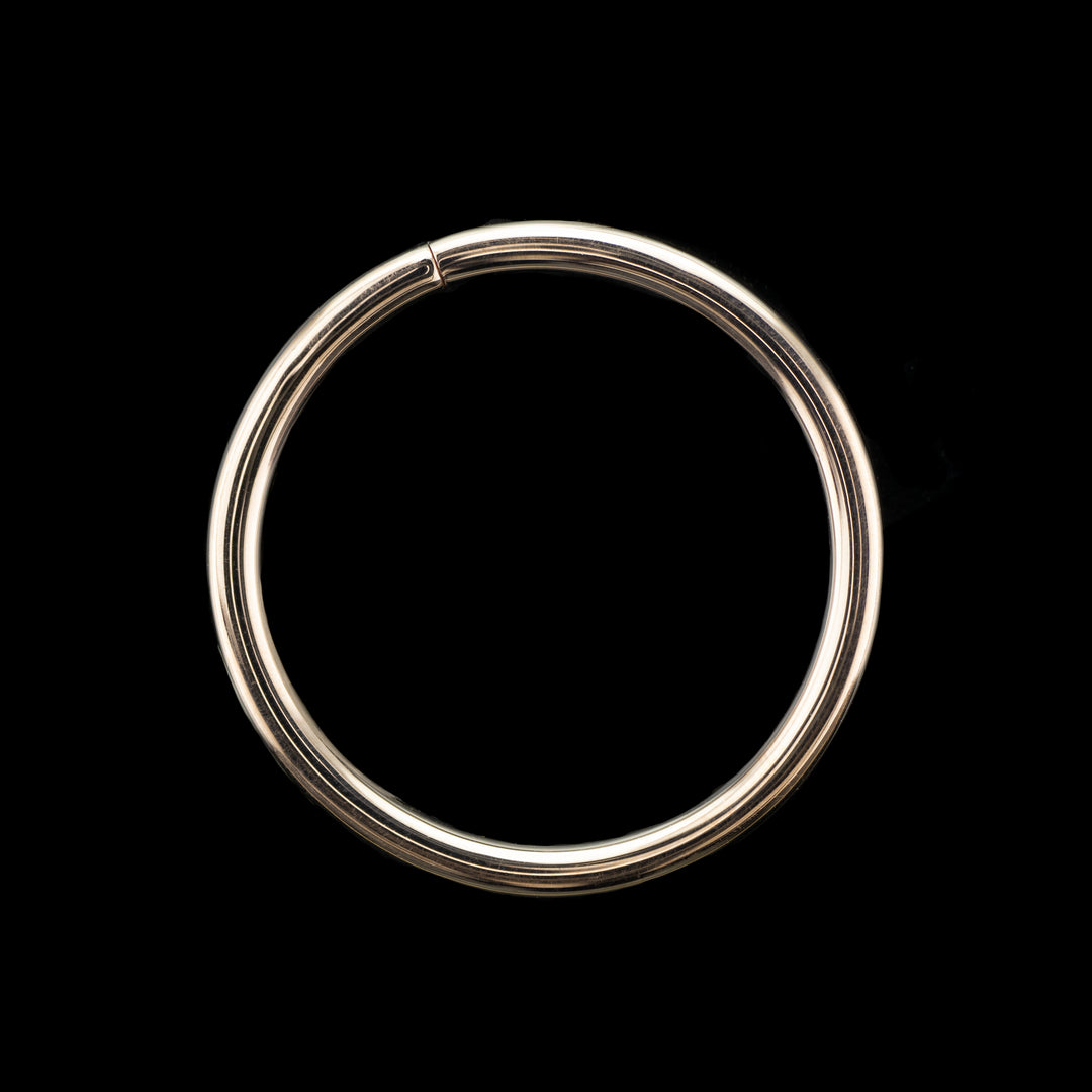 Solid gold seamless hoop on a black background. A high polish ring for belly, navel, nostril, daith, cartilage, helix, rook, tragus, earlobe piercings. 