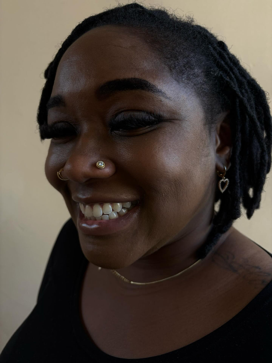 Photo of a smiling client with a new nostril piercing. They're wearing a gold end from Anatometal in they're nostril.
