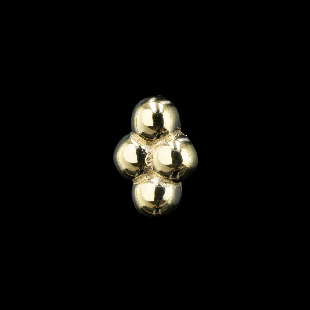 Side view of  a yellow gold piece of body jewelry on a solid black background. This design consists of 4 gold balls sawdered together in a diamond shape. 