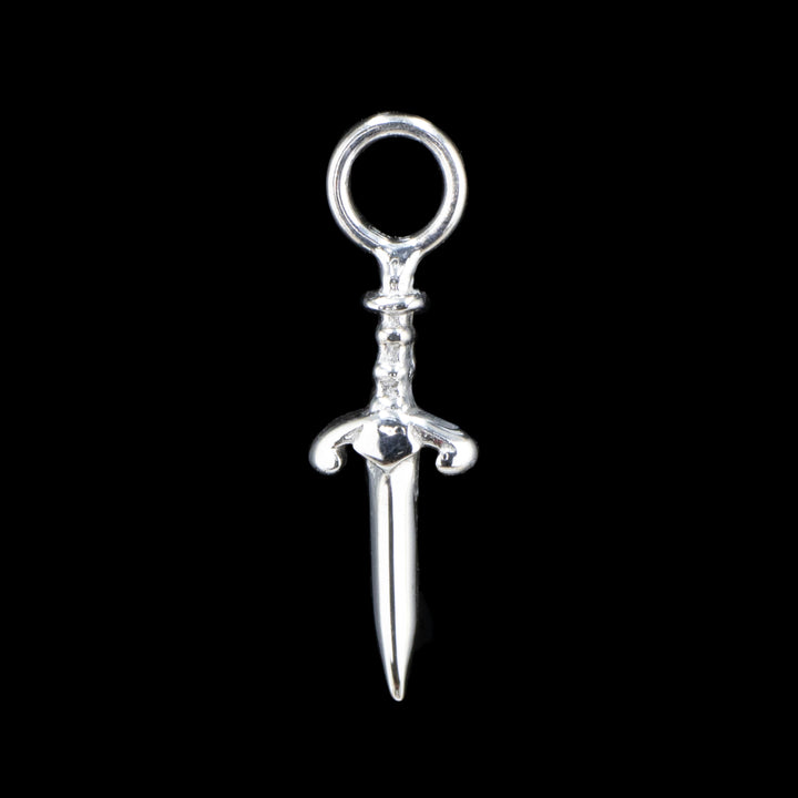 A white gold piece of jewelry on a black background. A dagger with a decorative hilt and a jump ring at the top.