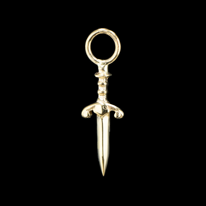 A yellow gold piece of jewelry on a black background. A dagger with a decorative hilt and a jump ring at the top.