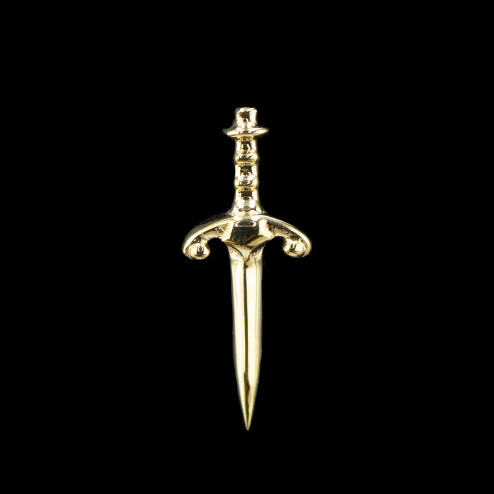 A yellow gold piece of jewelry that is a dagger with a decorative hilt.  