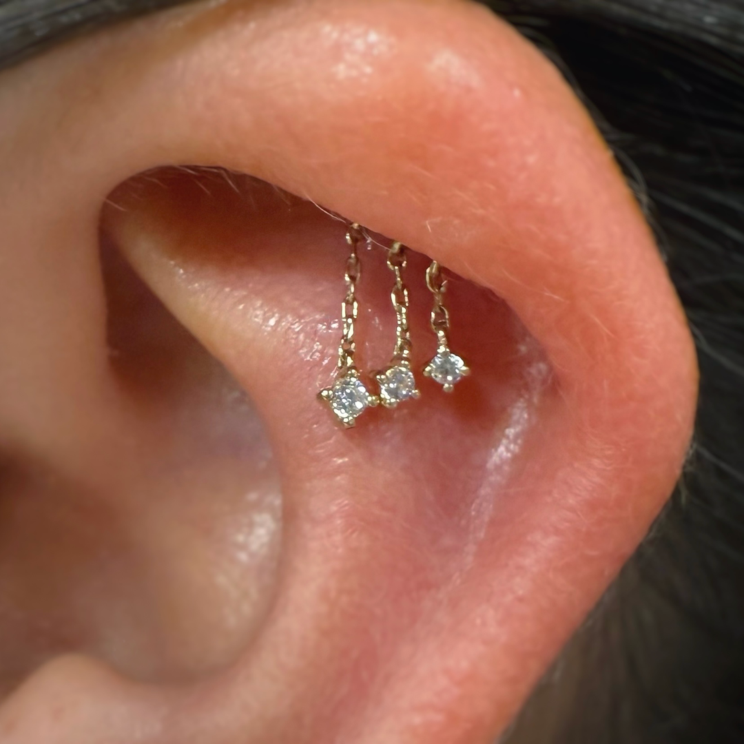 A close up of an earing with a hidden helix piercing wearing a yellow gold cascade threadless end. 