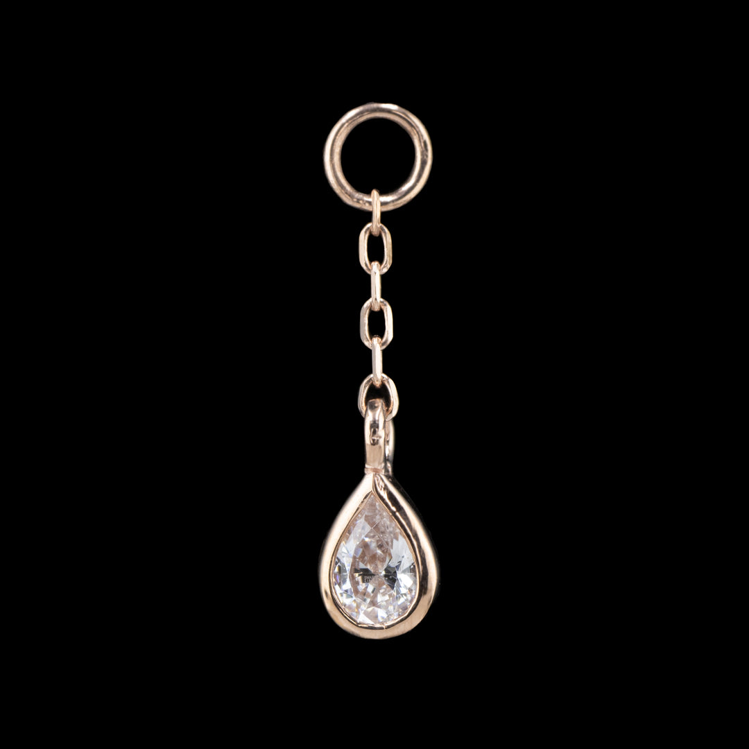 a rose gold body chain charm on a black background. The piece is a length of cable chain attached to a jump ring with a bezel set pear Cubic Zirconia on the end.