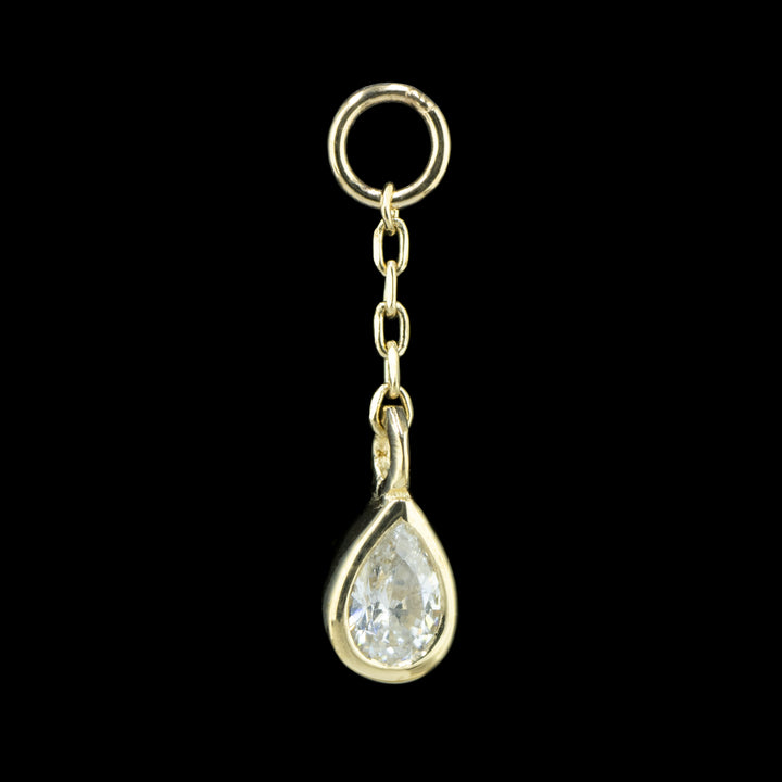 a yellow gold body charm on a black background. The piece is a length of cable chain attached to a jump ring with a bezel set pear Cubic Zirconia on the end.