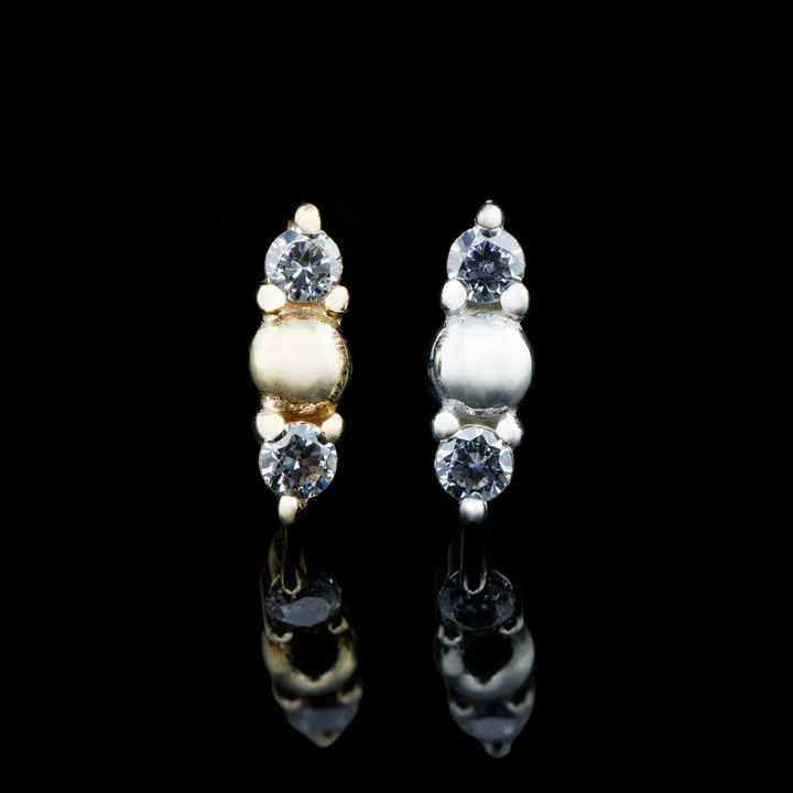 Two Crushing threadless ends on a black background, one in yellow gold and one in white gold. This end features a gold dome at the center with two Swarovski Crystals on top and bottom of each.