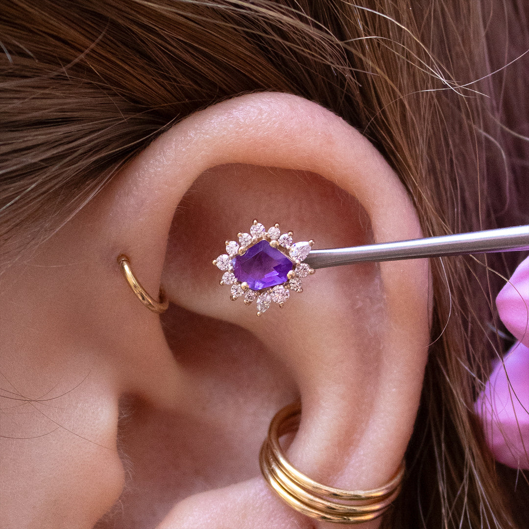 Close-up of the upper half of an ear with the amethyst eye candy being held up to a flat placement.