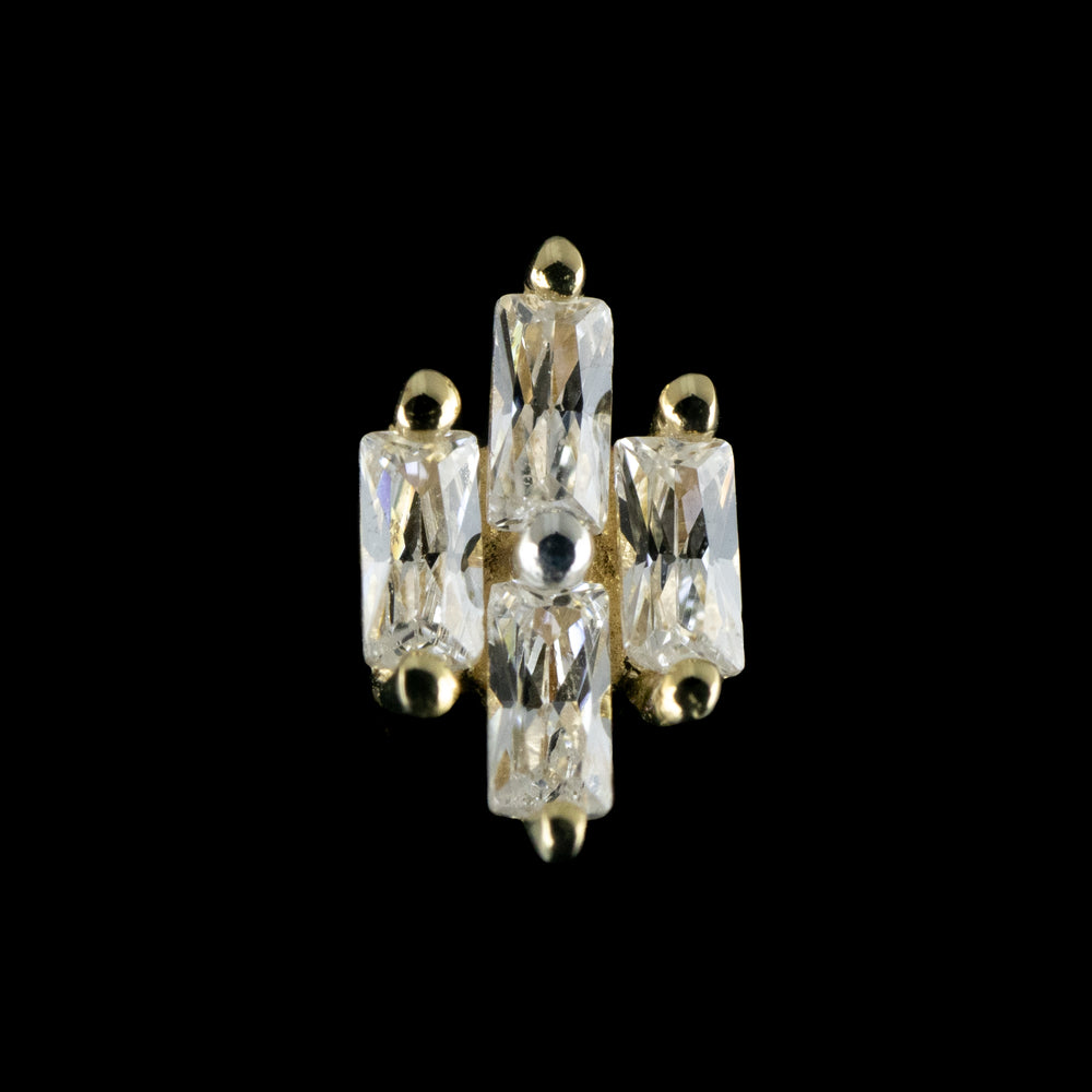 A yellow gold piece of body jewelry on a black background. The design is made up of 4 baguette cut stones set in a diamond shape.