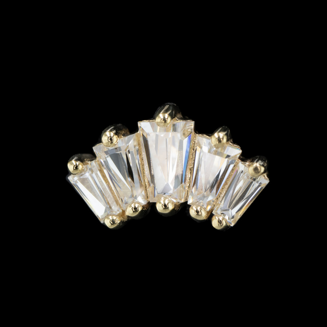 yellow gold piece of jewelry on a black background. This piece features 5 tapered baguettes set in prongs. The center cubic zirconia is the largest gem with the outer gems descending in size. 