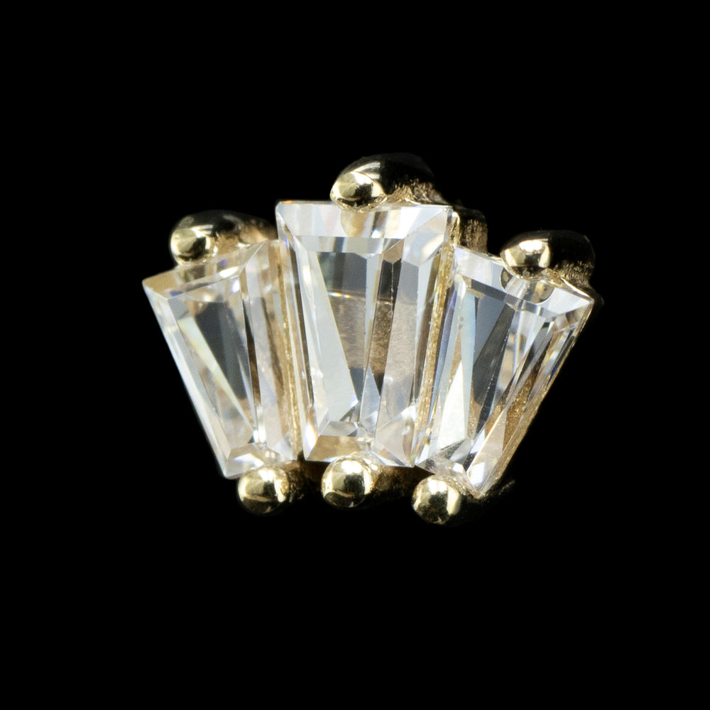 A yellow gold threadless end featuring three tapered baguette Swarovski crystals set on a black background