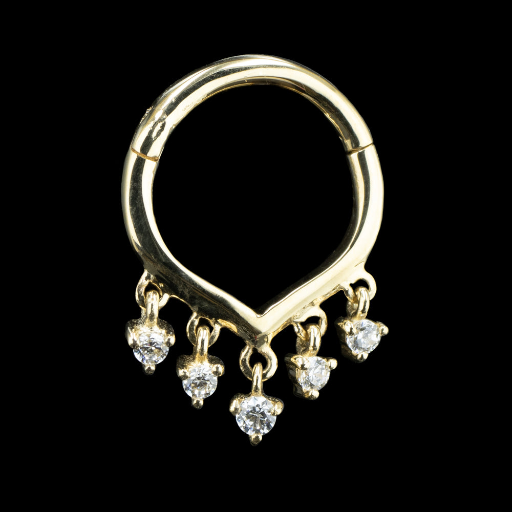 A yellow gold ring on a black background with a slight v shape and 5 CZs dangling on the bottom of the ring.
