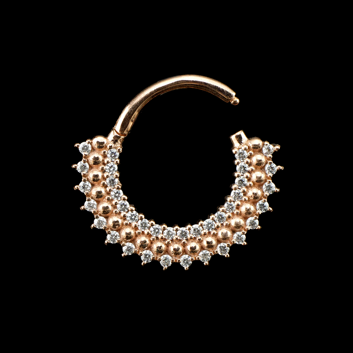 Heart of Gold ring in rose gold from Buddha Jewelry set on a black background. This rings design is made up of a row of gold beads sandwiched by two rows of small Swarovski crystals.
Septum piercings, Daith piercings