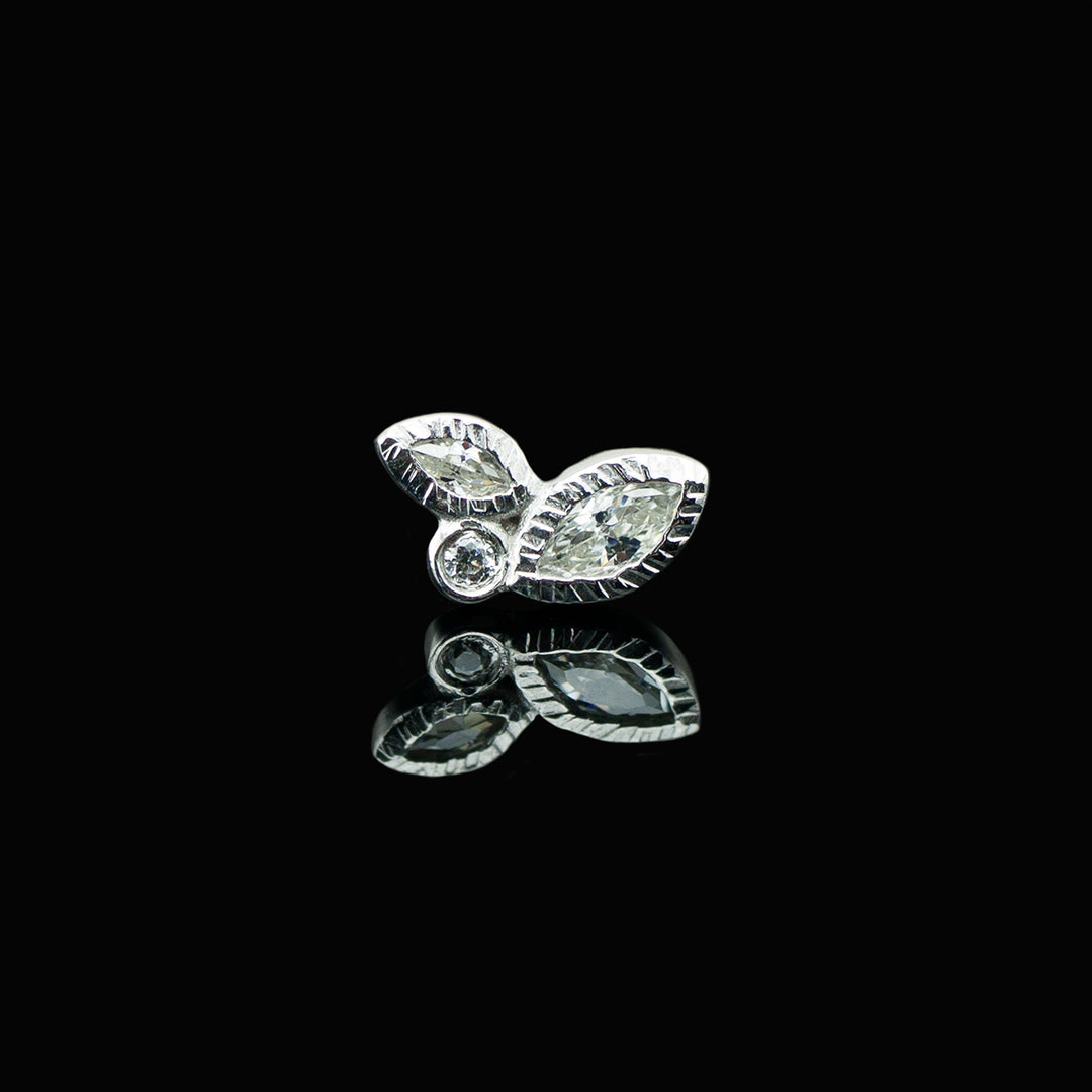 A white gold piece of body jewelry on a black background. The piece consists of two varying sizes of marquise cut white cz offset with a round white cz set in the center. 
