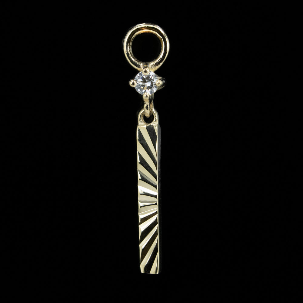A yellow gold labyrinth charm on a black background