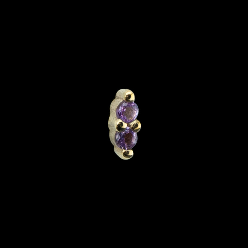 A solid yellow gold piece of body jewelry on a black background. Jewelry is solid 14 karat. The design is two small round cut gems set next to each other in prongs. This piece is dainty and small perfect as an accent piece. 