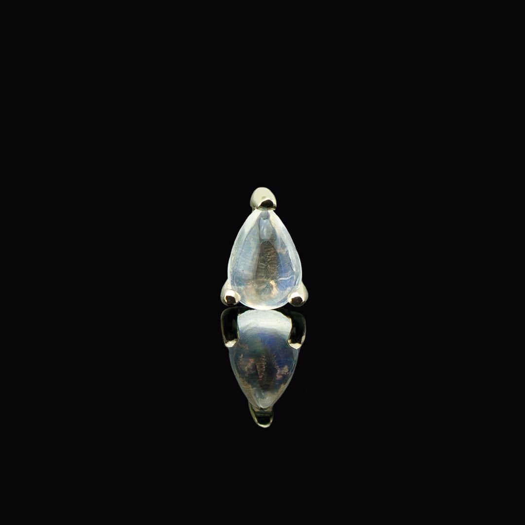 Teardrop shaped gemstone set in three yellow gold prongs on a black background.