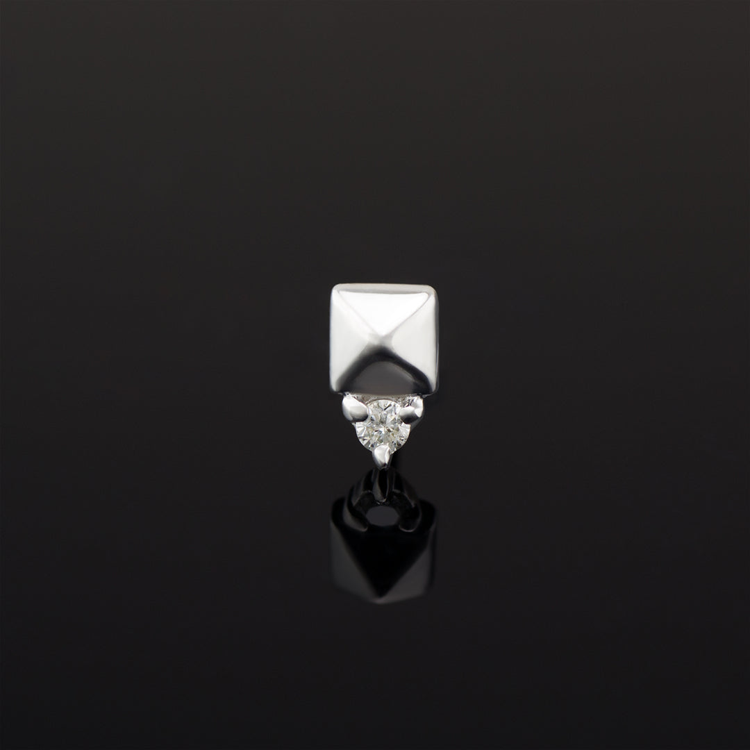 A push pin piece of white gold body jewelry made of solid 14 karat gold. The design is a pyramid shape made of gold with a genuine diamond set in three prongs on one side.