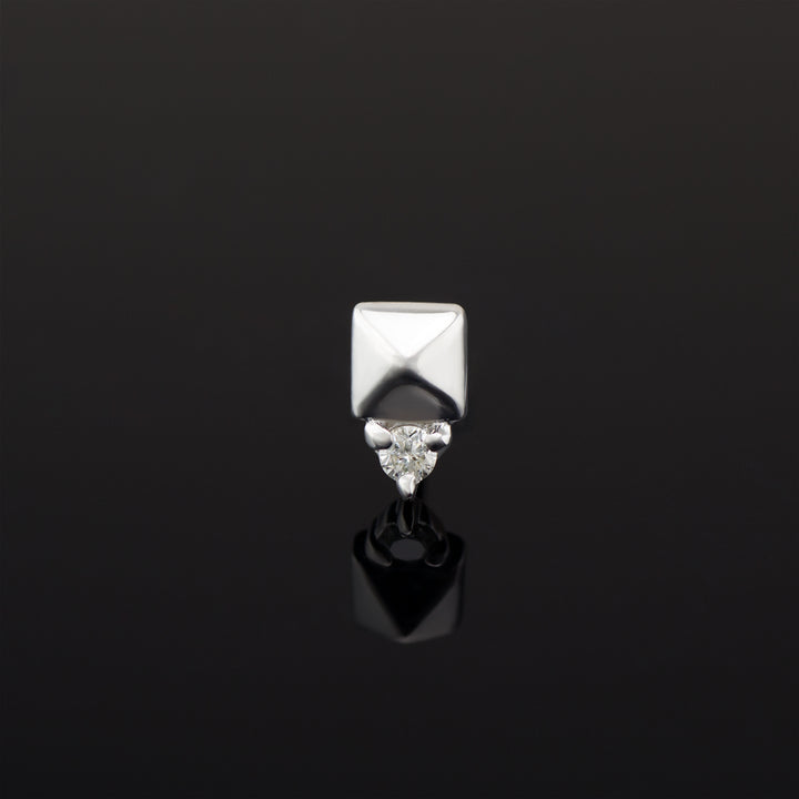 A push pin piece of white gold body jewelry made of solid 14 karat gold. The design is a pyramid shape made of gold with a genuine diamond set in three prongs on one side.