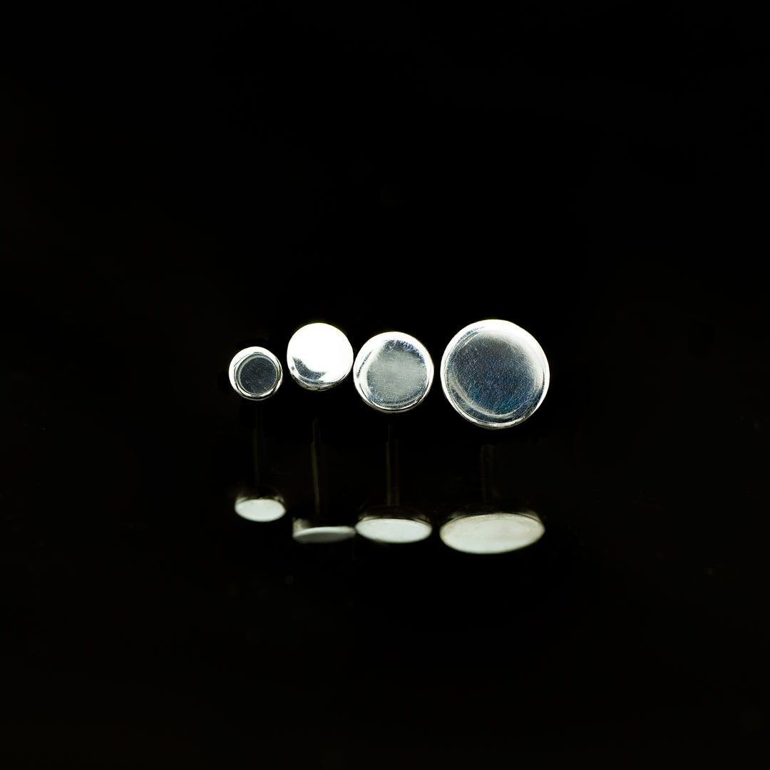 A row of white gold circles arranged in ascending sizes on a black background.