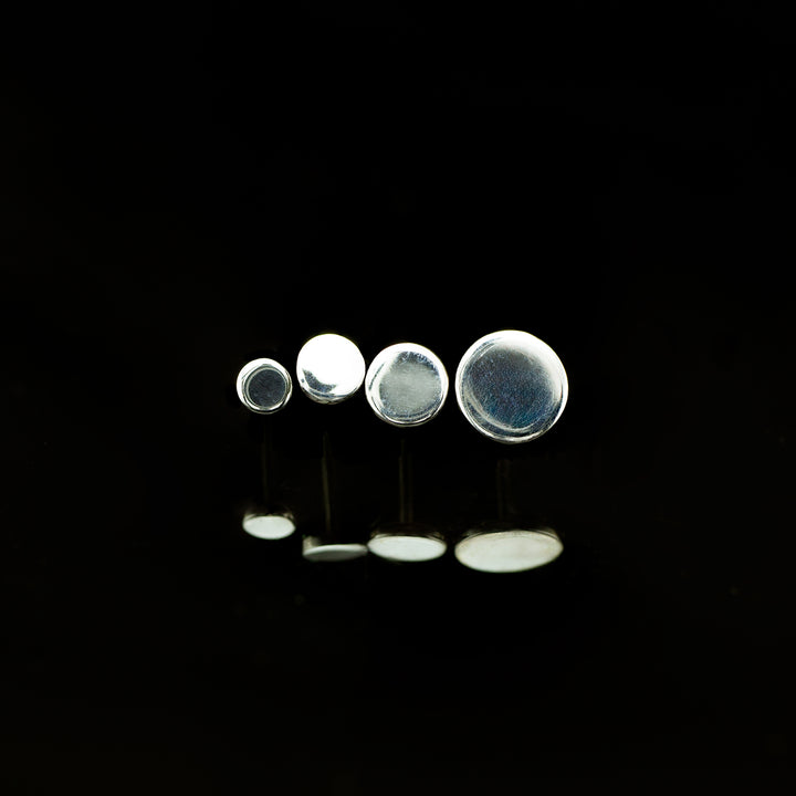A row of white gold circles arranged in ascending sizes on a black background.