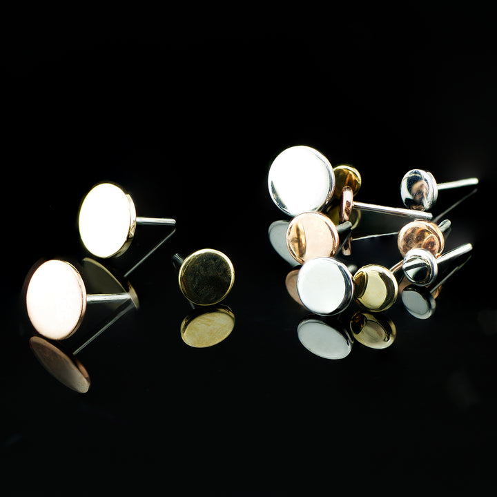 Set of yellow, rose, and white gold round disks on a black background.