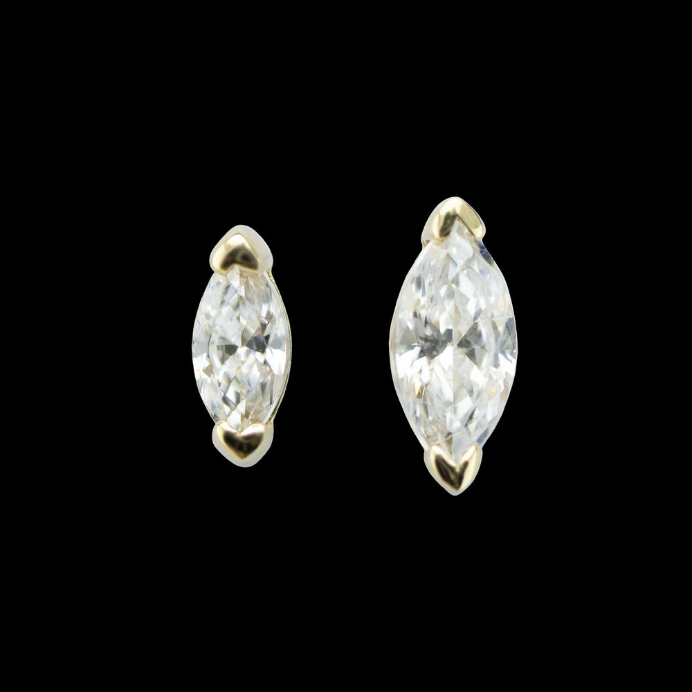 Two piece of yellow gold body jewelry on a solid black background. the piece on the left is 3mm in length and the piece on the right is 4mm in length. The piece is a marquise cut white cubic zirconia set in v shaped prongs on both points of the gem. 