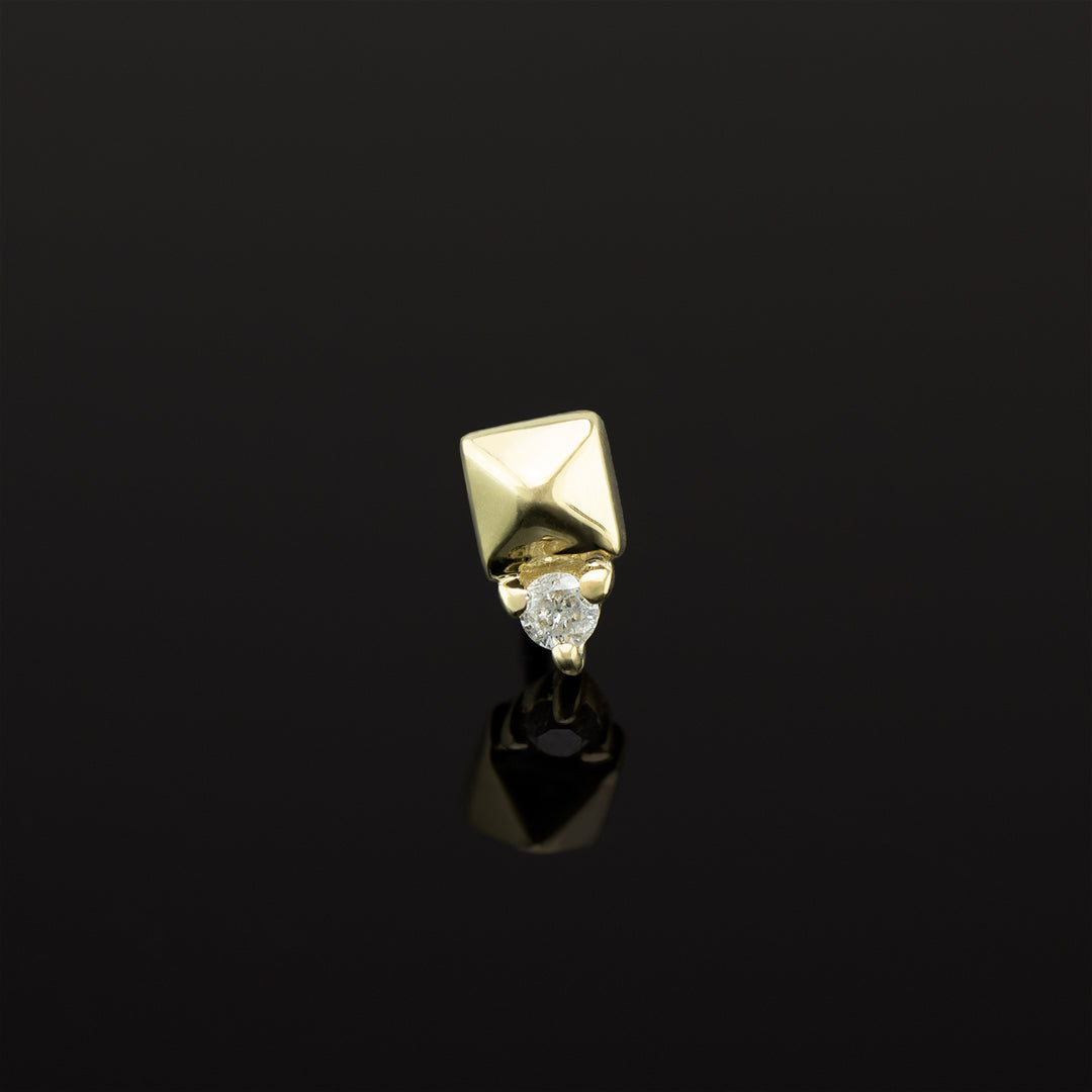 A push pin piece of yellow gold body jewelry made of solid 14 karat gold. The design is a pyramid shape made of gold with a genuine diamond set in three prongs on one side.
