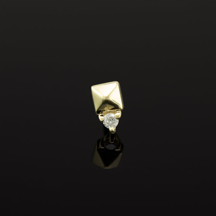 A push pin piece of yellow gold body jewelry made of solid 14 karat gold. The design is a pyramid shape made of gold with a genuine diamond set in three prongs on one side.