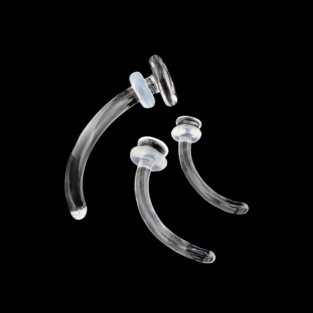 Three different sizes of glass curved retainers on a black background. Each retainer comes with a silicone o-ring to keep it secure in your piercing. 