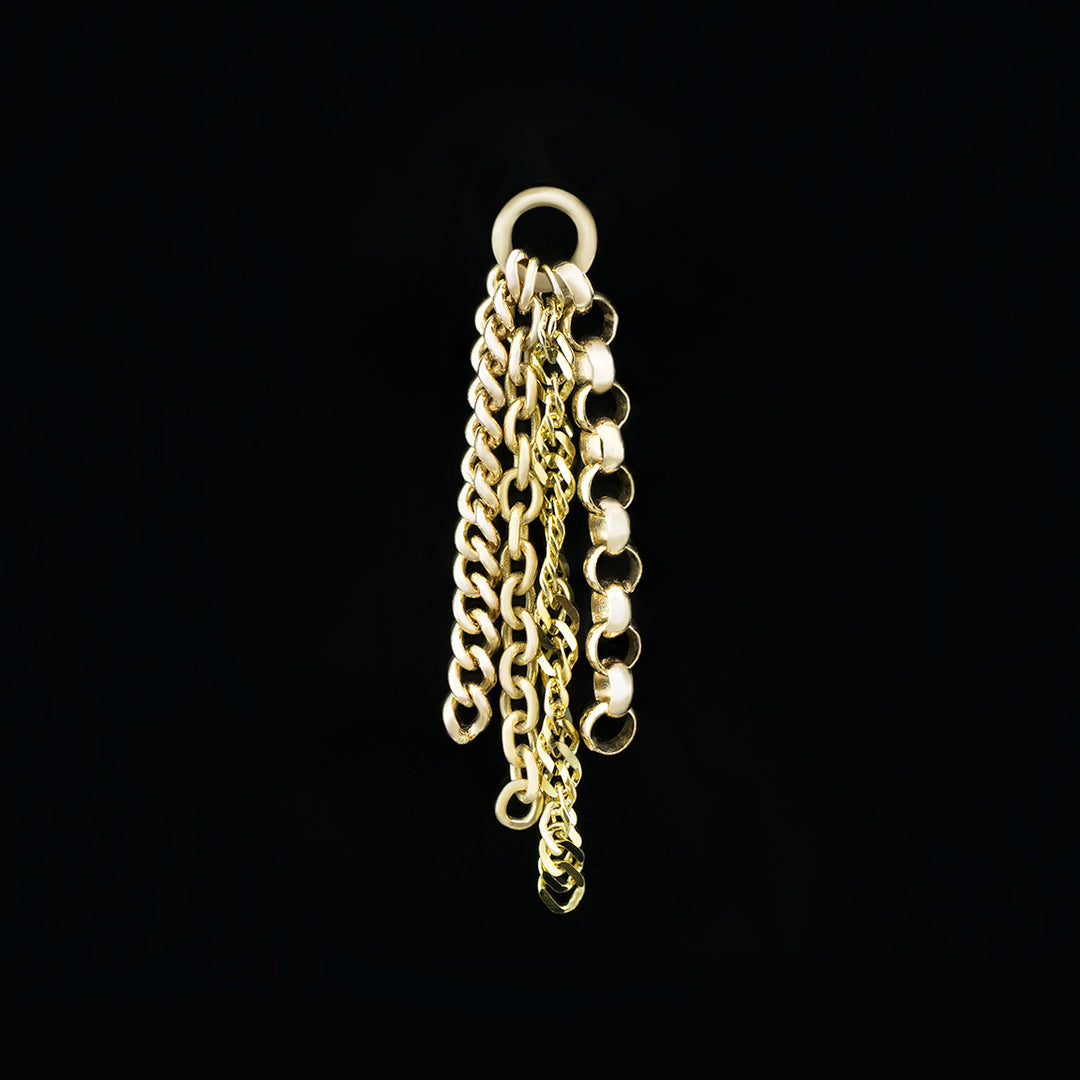 A yellow gold body jewelry charm picture on a black background. There are four varying lengths of chain on a 16 gauge jump ring. Each chain is a different style of chain including rolo, cable, curb, and a flattened light catching curb chain. 