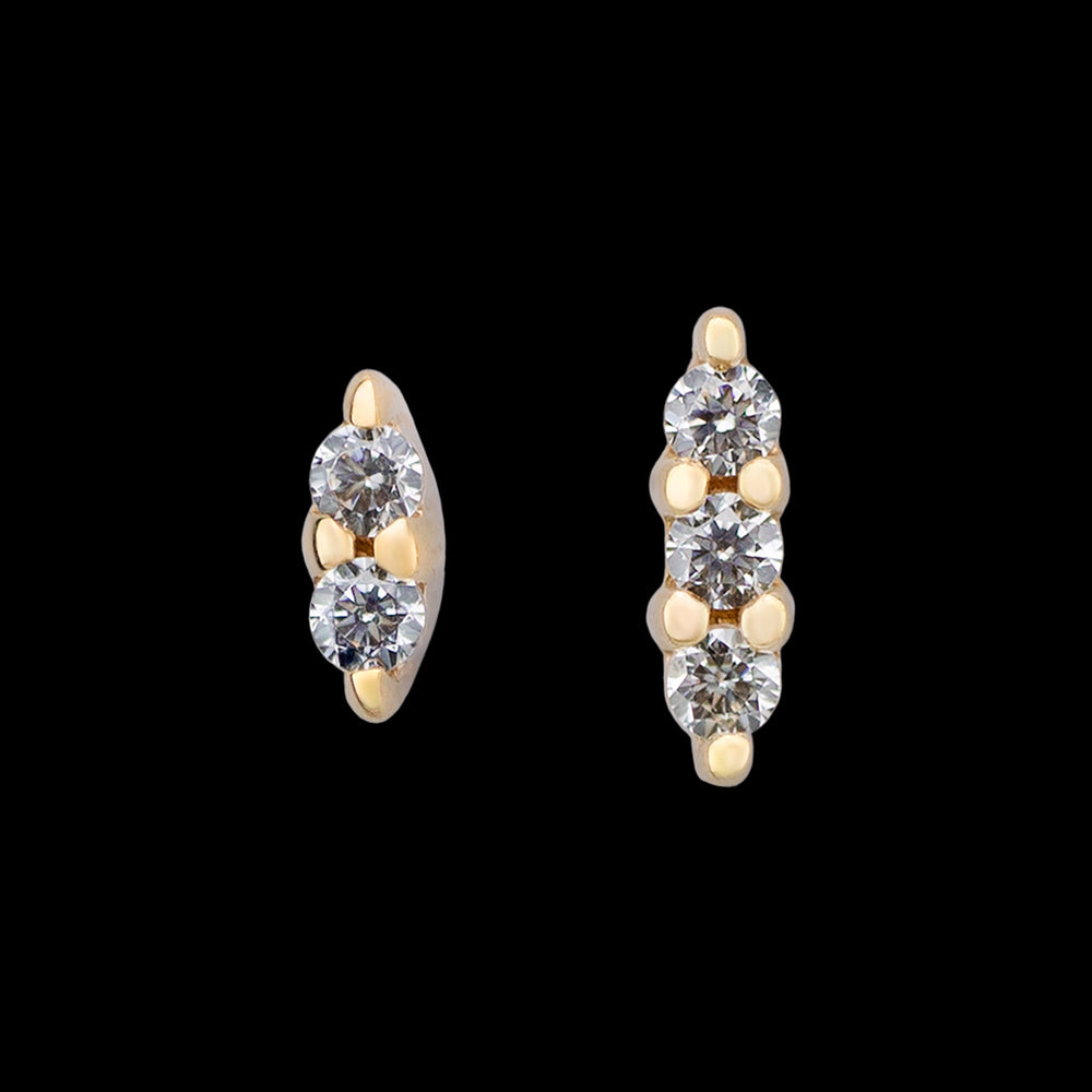 Yellow gold Mishka 2 and Mishka 3 ends from Buddha Jewelry on a black background. Mishka 2 is made up of two small white CZs set in prongs next to each other. Mishka 3 is made up of 3 small white CZs set in prongs in a row. 