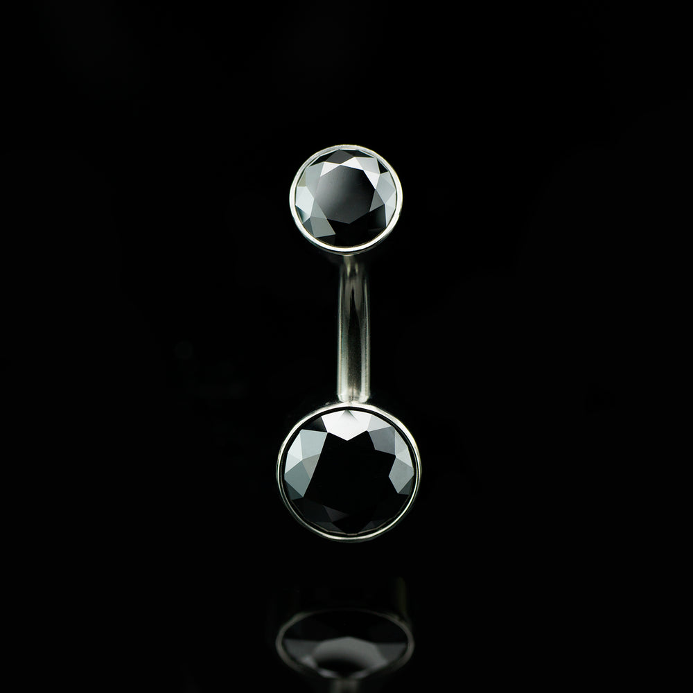 Belly button ring with black gemstones on a black background