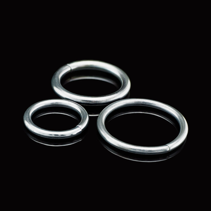 Three black niobium rings of varying sizes on a black background.