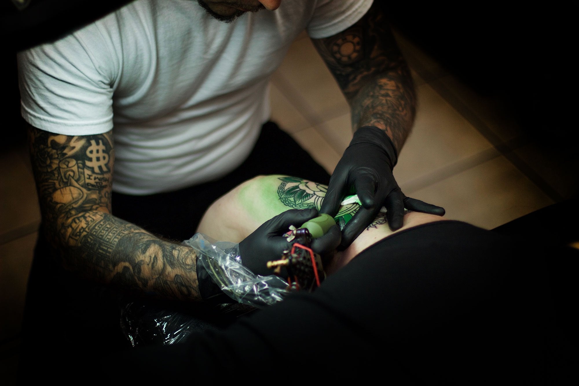 Tattoo artist working on a tattoo on a clients thigh. 