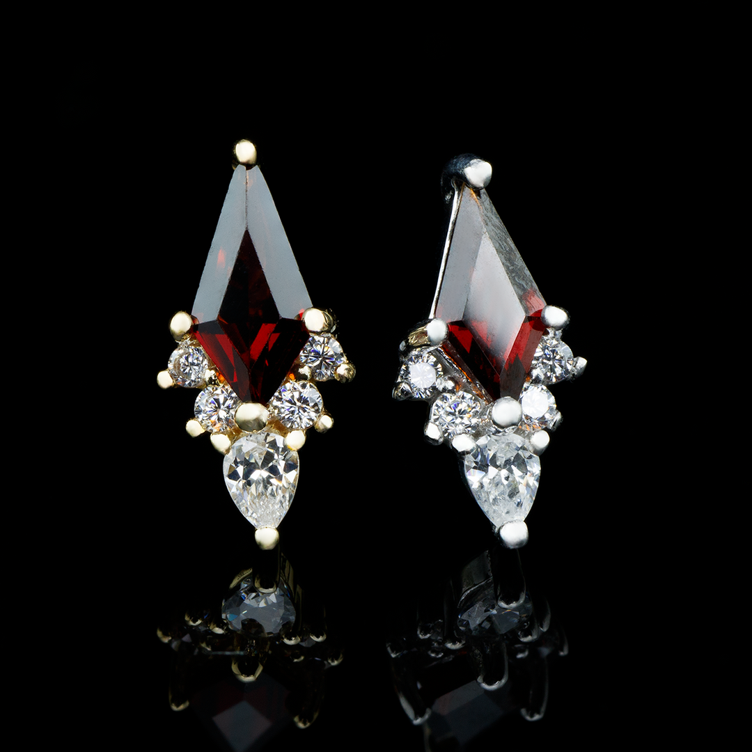 Two Afterglow threadless ends on a black background. This design features a large kite cut Garnet with 4 small round cut Cz and one pear cut cz at the bottom. 
