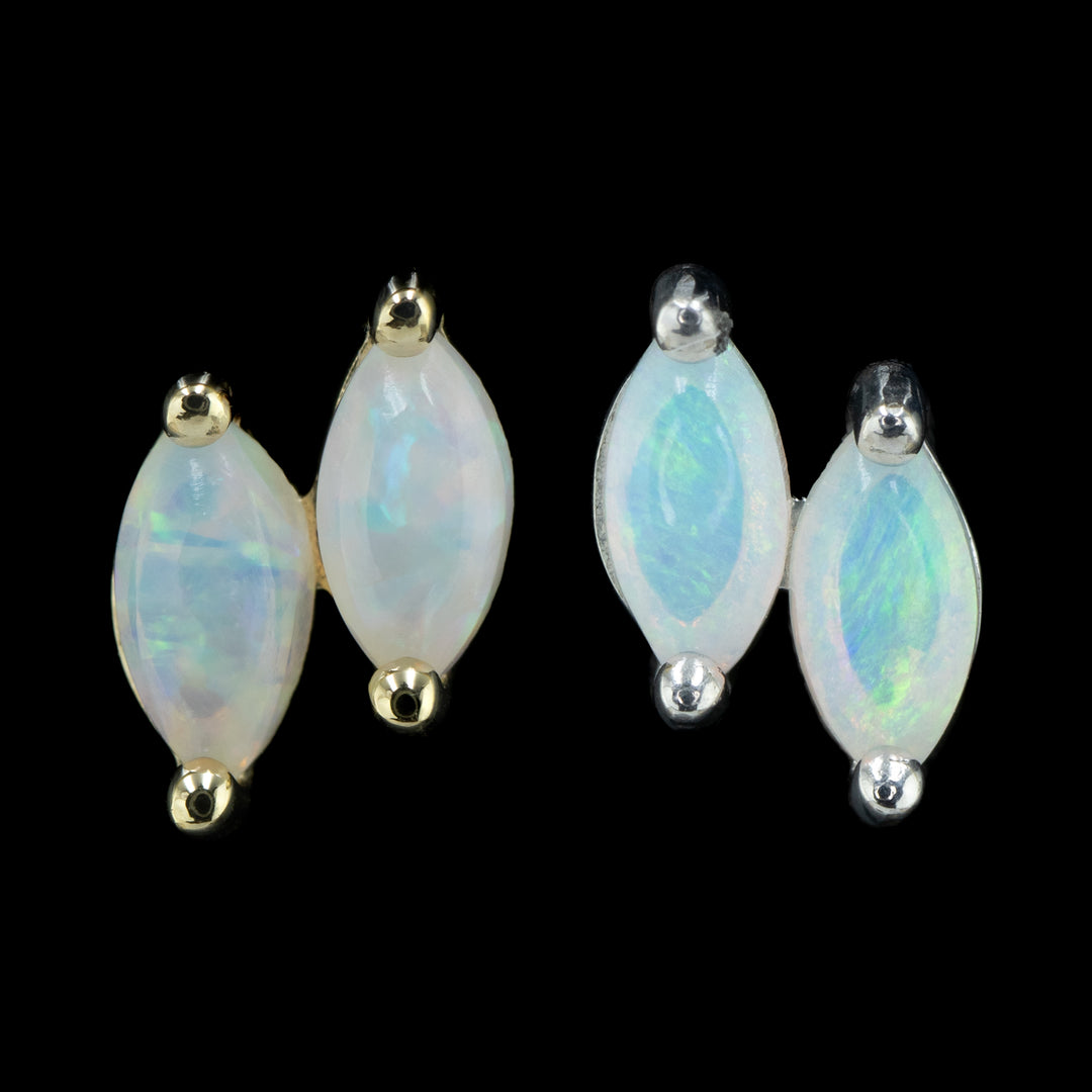 two pieces of body jewelry on a black background. one in yellow gold and one in white gold. both pieces are two offset genuine marquise cut opals held by two prongs each. 