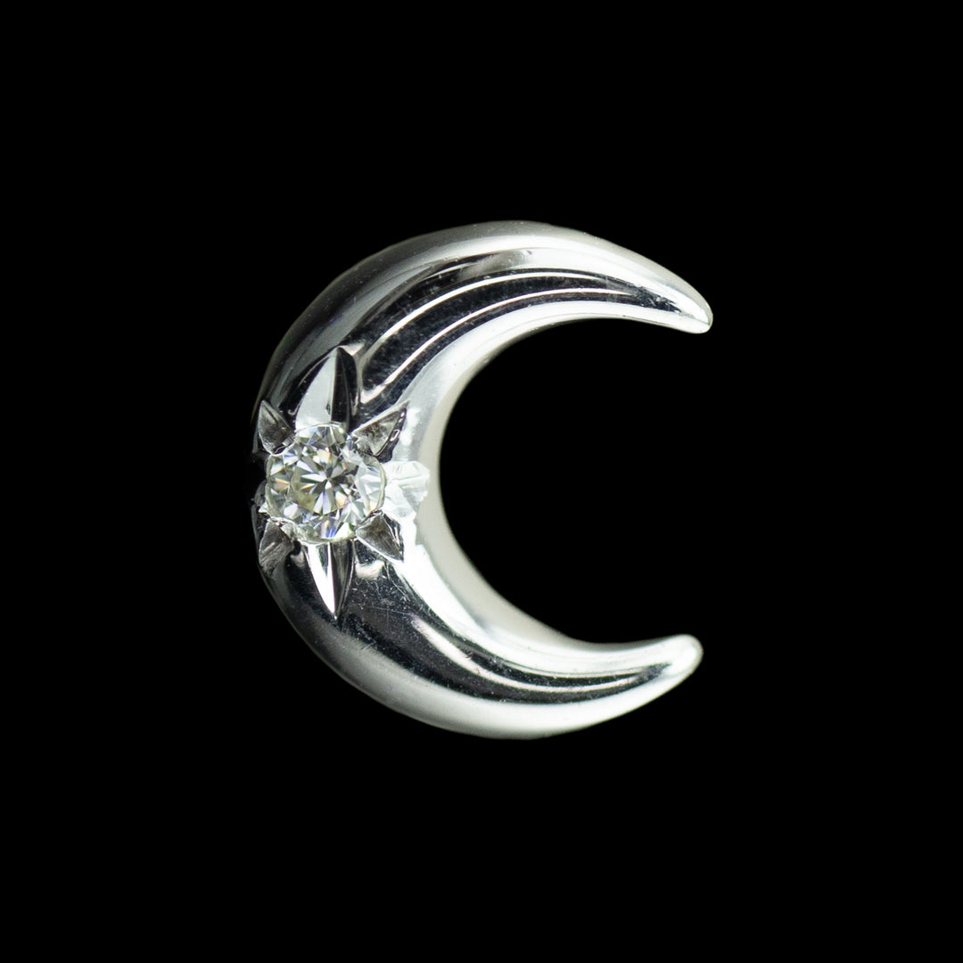 white gold body jewelry in the shape of a moon with a white cubic zirconia center. 